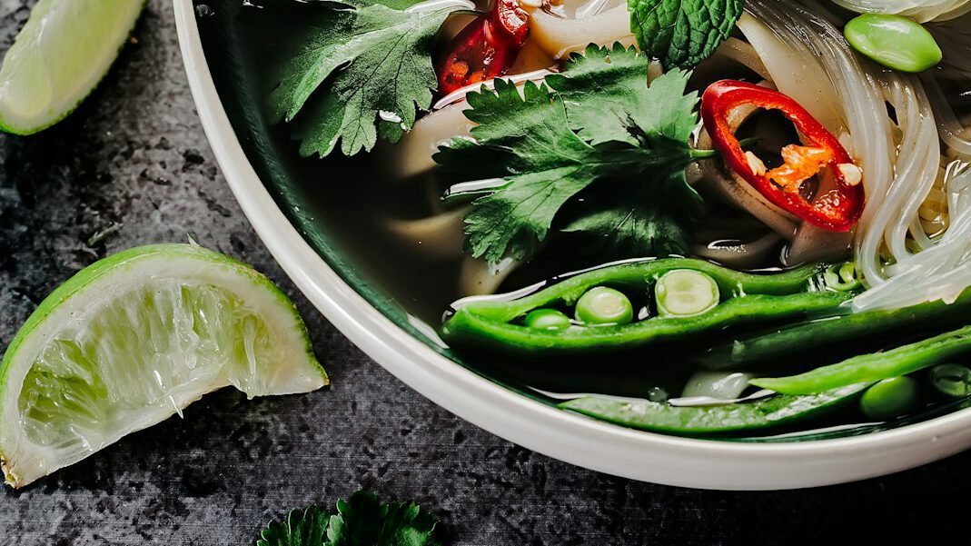 asian soup bowl with vegetables, chili, and lime